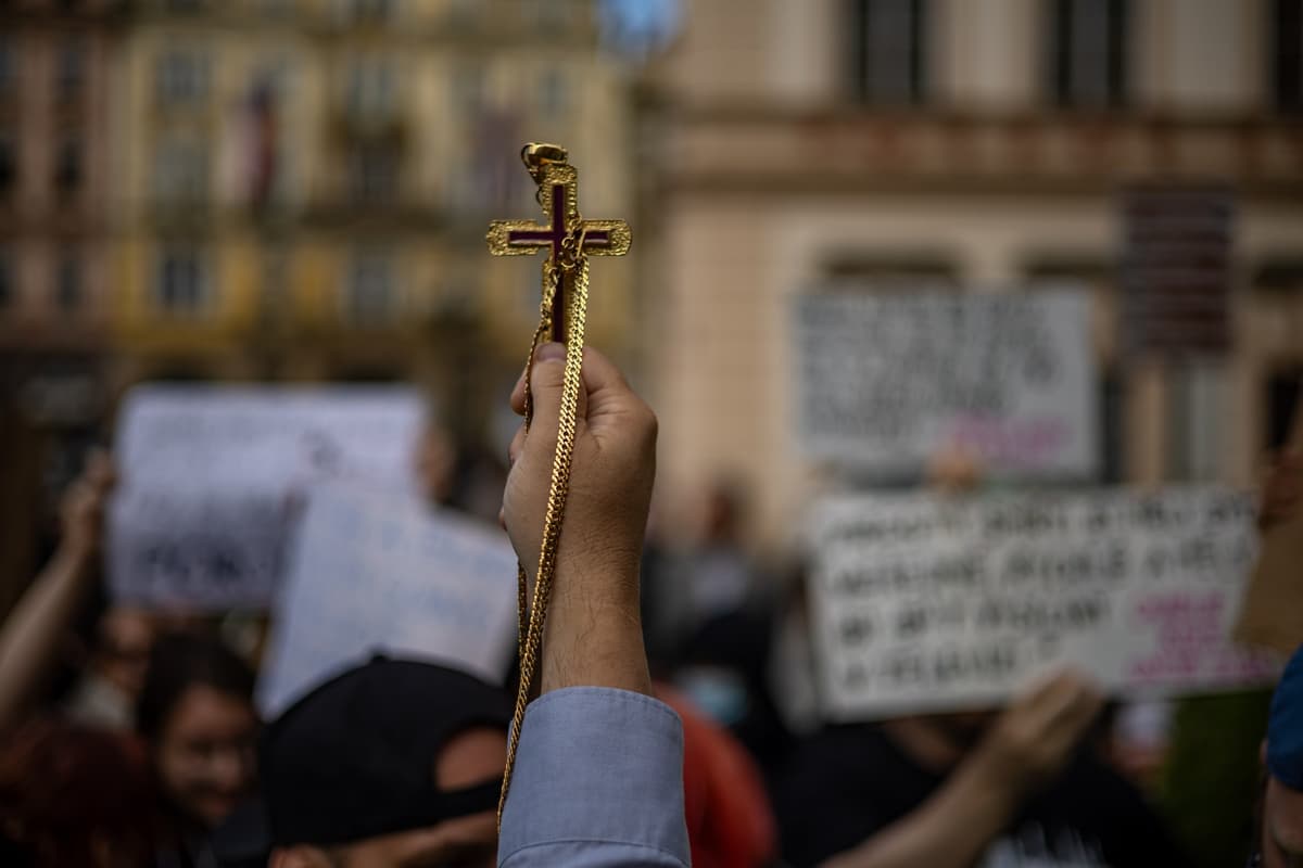 Účastník omše za Charlieho Kirka drží kríž pred ľavicovými protestujúcimi. Foto MARTIN DIVISEK / EPA / Profimedia