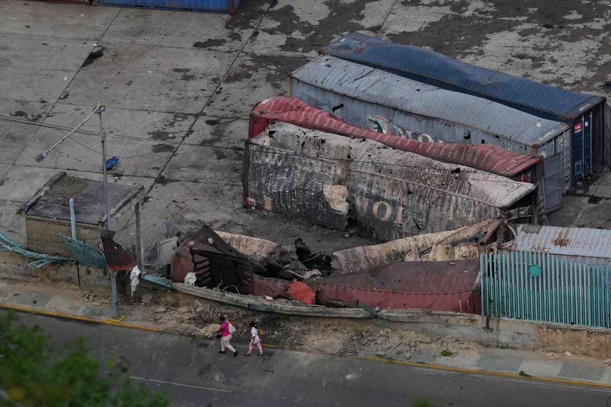 Ľudia kráčajú okolo zničených kontajnerov v prístave La Guaira po výbuchoch vo venezuelskej metropole Caracas 3. januára 2026. Foto: TASR/AP
