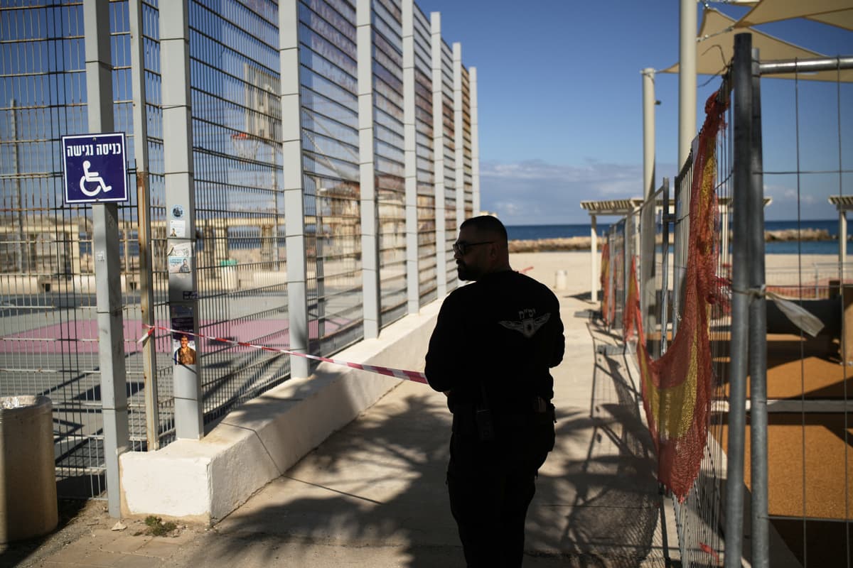 Policajt uzatvára pláž po tom, čo sa v Izraeli rozozvučali sirény. Foto: TASR/AP/ Leo Correa