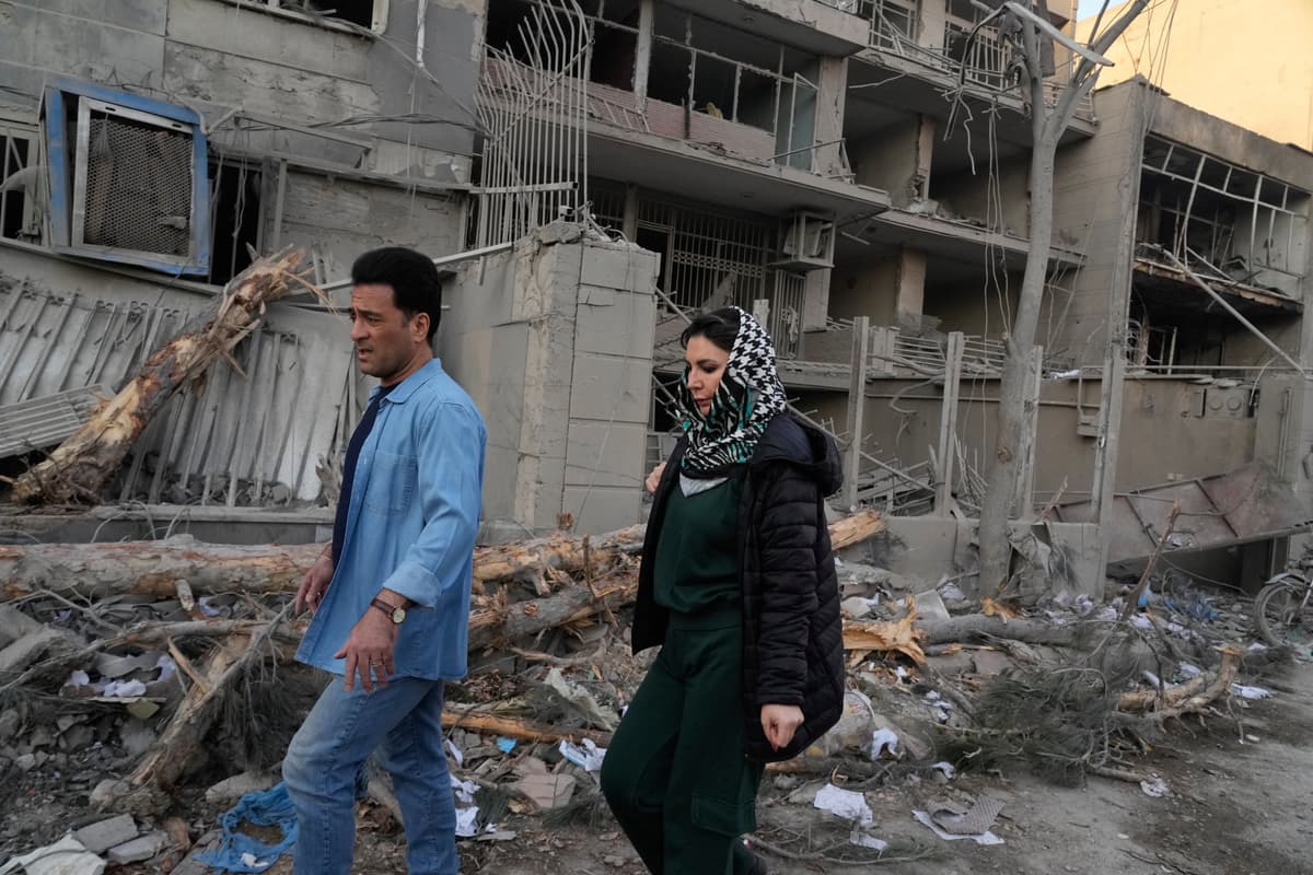 Ľudia prechádzajú pri zničených budovách po útokoch americkej a izraelskej armády v Teheráne v Iráne. Foto: TASR/AP