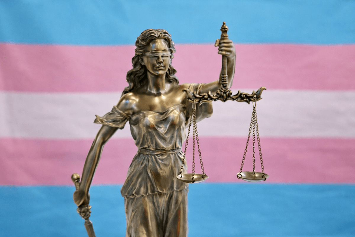 Spravodlivosť s transgender vlajkou v pozadí. Foto Pexels.com/ChatGPT