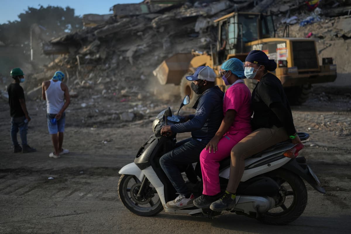 Zdravotníci prechádzajú okolo trosiek budov po ničivom zemetrasení v meste La Guaira na severe Venezuely. Foto: TASR/AP