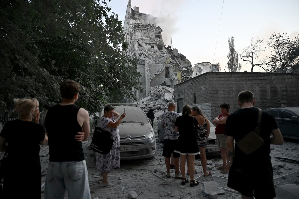 Miestni sledujú, ako záchranári pracujú v poškodenej obytnej budove po raketových útokoch na Kyjev 2. júla 2026. Foto: Genya Savilov / AFP / AFP / Profimedia
