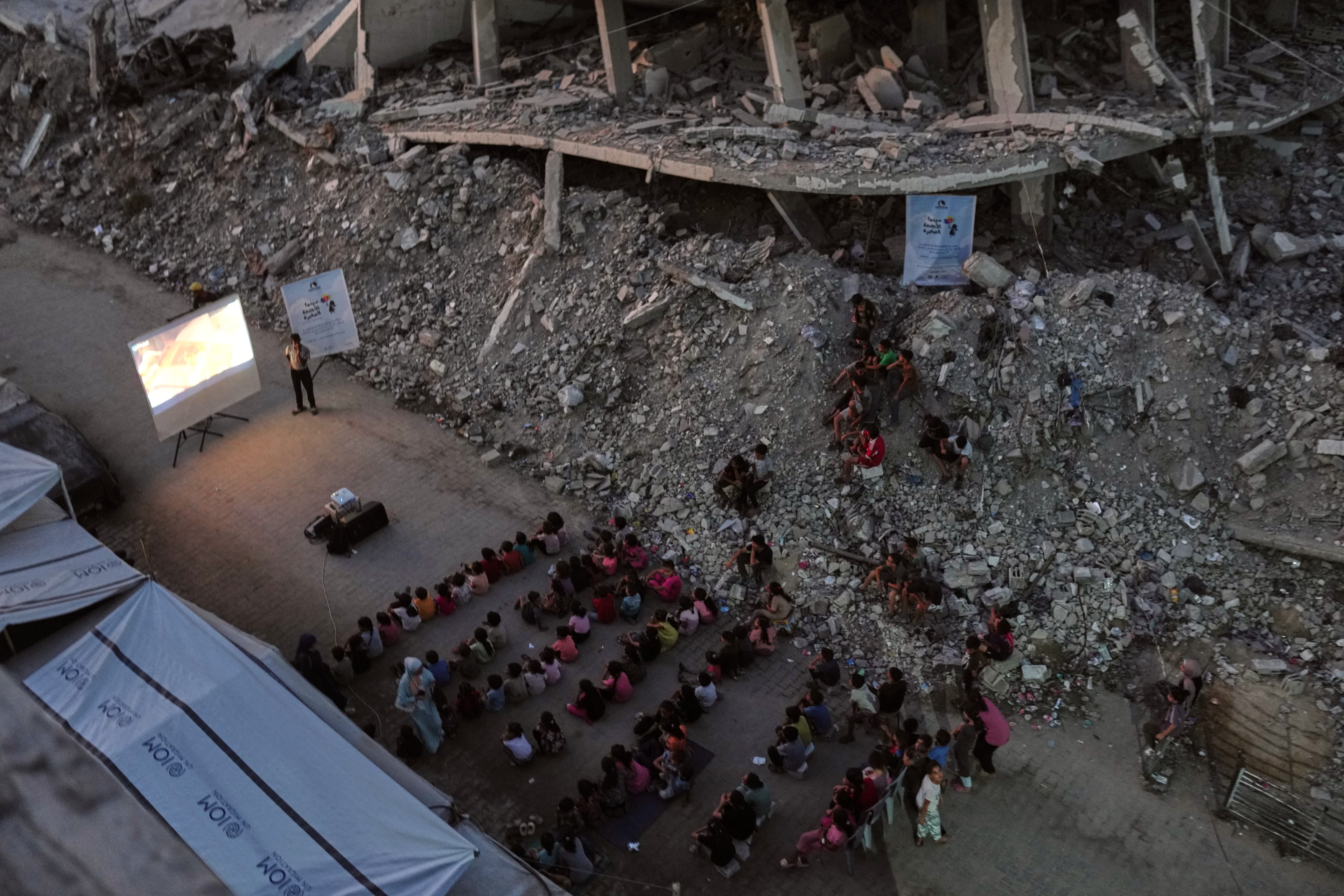 Vysídlené palestínske deti pozerajú rozprávku medzi troskami zničených budov po izraelských leteckých útokoch v meste Gaza v utorok 8. septembra 2026. Foto: TASR/AP