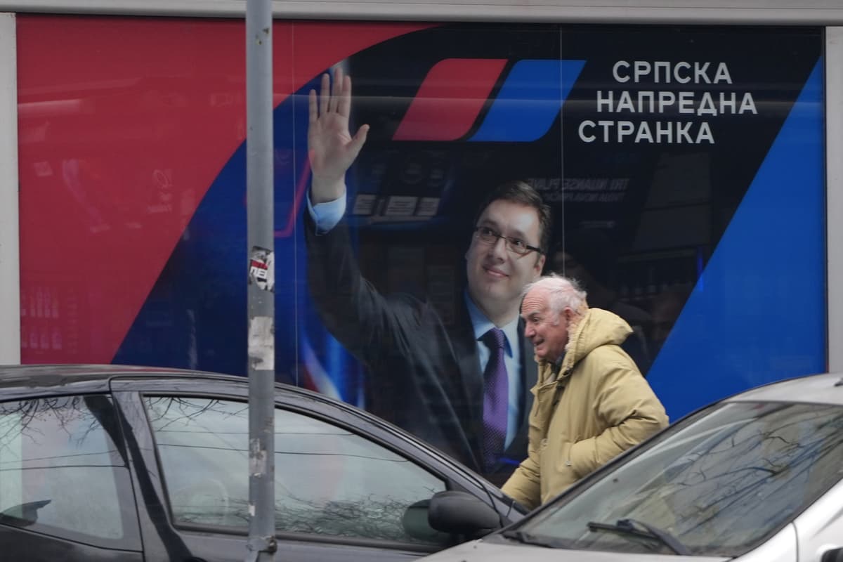 Na snímke zo 16. januára 2026 muž kráča okolo okna kancelárie Srbskej pokrokovej strany (SNS), v ktorom je bilbord s podobizňou Aleksandara Vučiča v Belehrade. Foto: TASR/AP