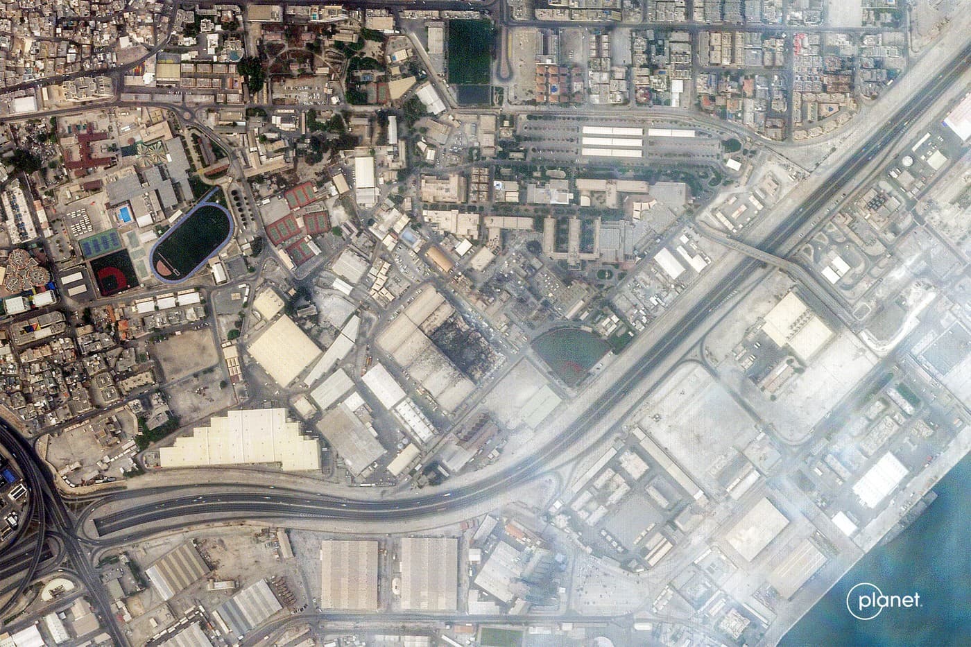 Satelitný snímok, zachytáva dym stúpajúci z poškodených častí námornej základne 5. flotily USA v bahrajnskej metropole Manáma. Foto: AFP / 2026 Planet Labs PBC / AFP / Profimedia