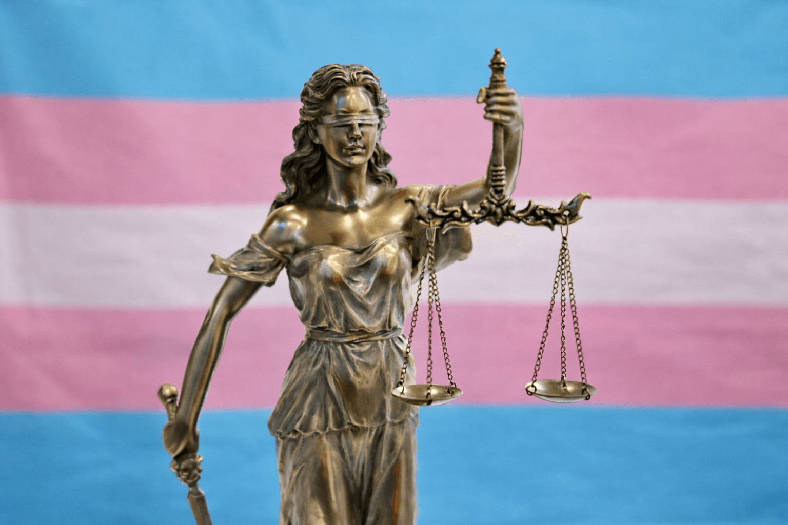 Spravodlivosť s transgender vlajkou v pozadí. Foto Pexels.com/ChatGPT