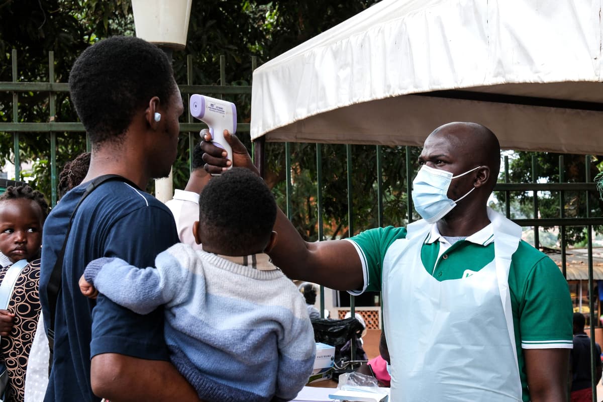 Pracovník nemocnice meria teplotu osobám pred vstupom do nemocnice v ugandskom meste Kampala v sobotu 16. mája 2026. Foto: TASR/AP