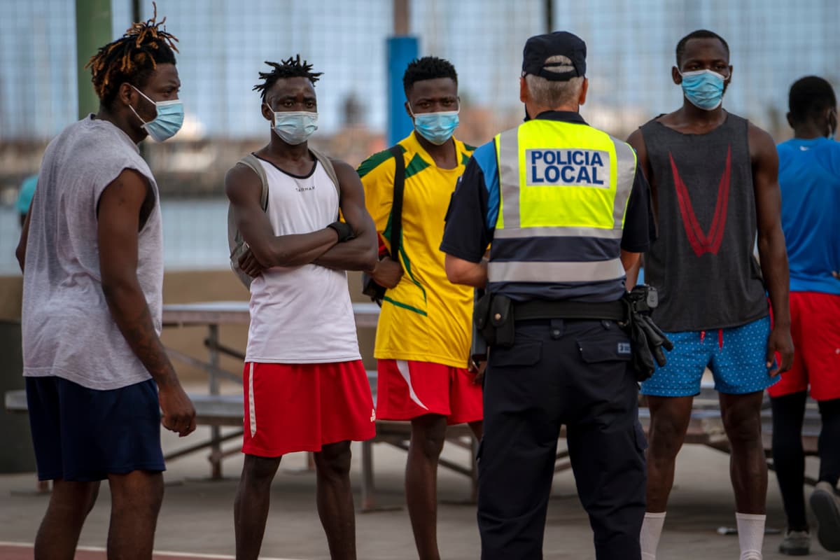 Španielsky policajt rozpráva s migrantmi a žiadateľmi o azyl. Foto: TASR/AP